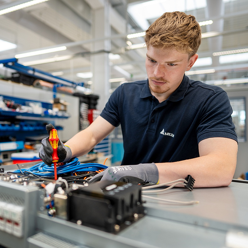 Ein Student hält einen Schraubenzieher in der Hand, um ein Bauteil zu reparieren.