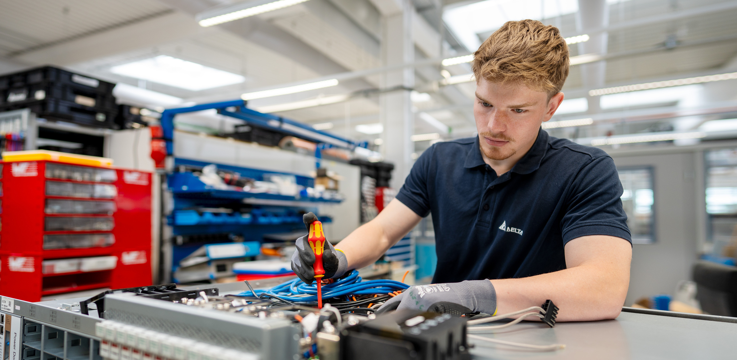 Ein Student hält einen Schraubenzieher in der Hand, um ein Bauteil zu reparieren.
