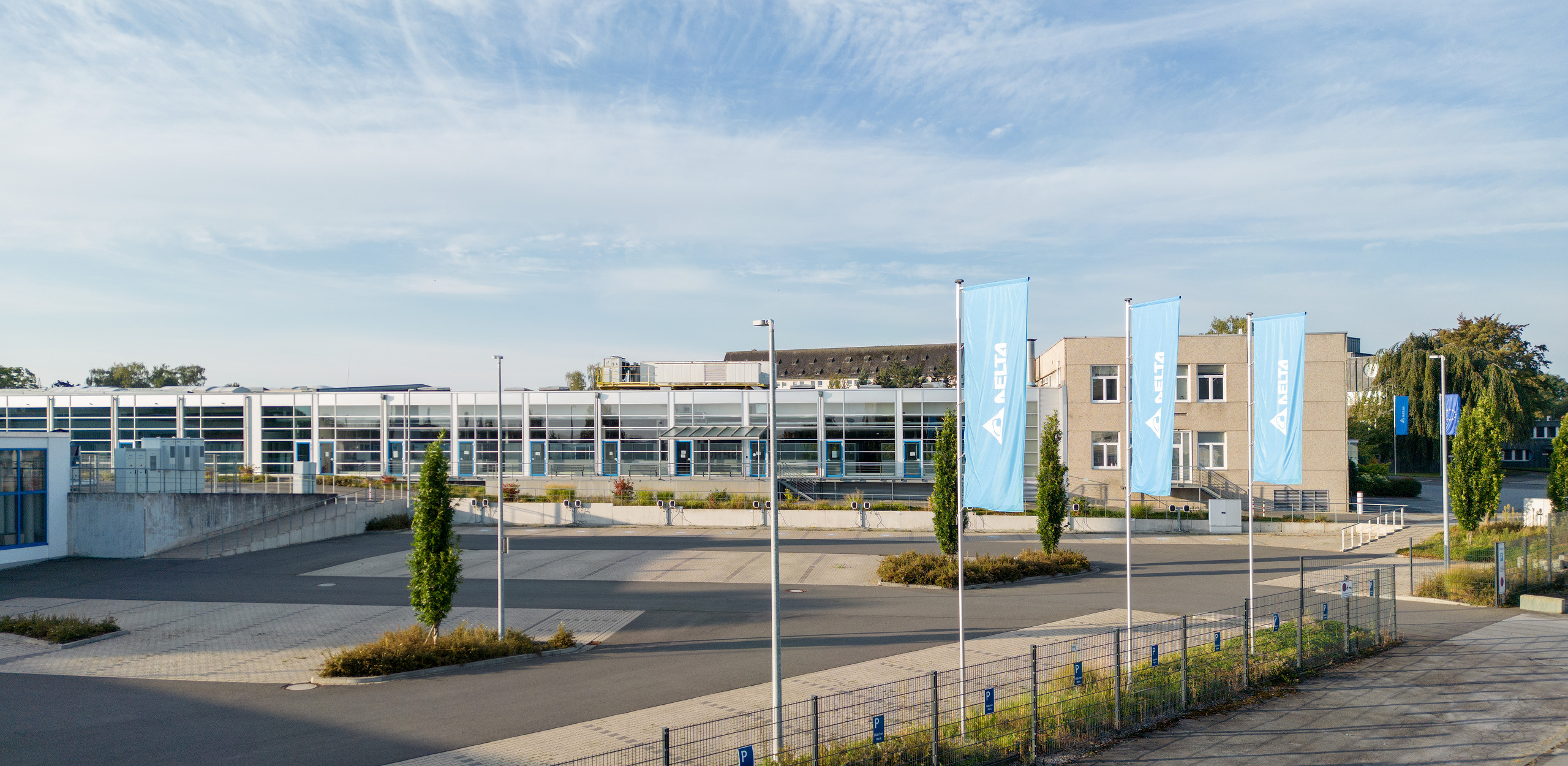 Gebäude Delta in Soest mit drei blauen Delta Fahnen im Vordergrund und zwei weiteren Fahnen im Hintergrund