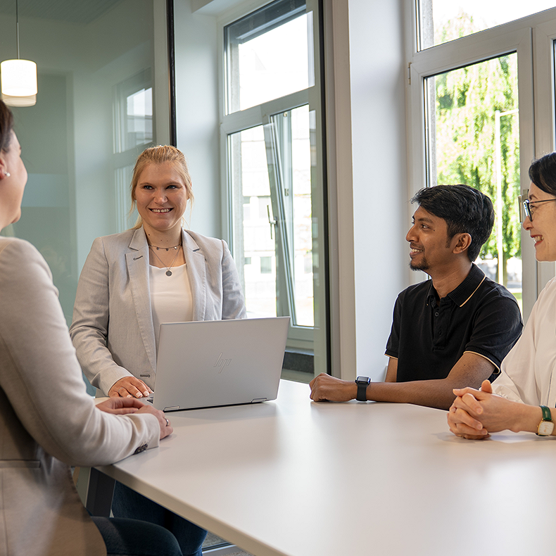 A woman welcomes three new employees, including two women and one man
