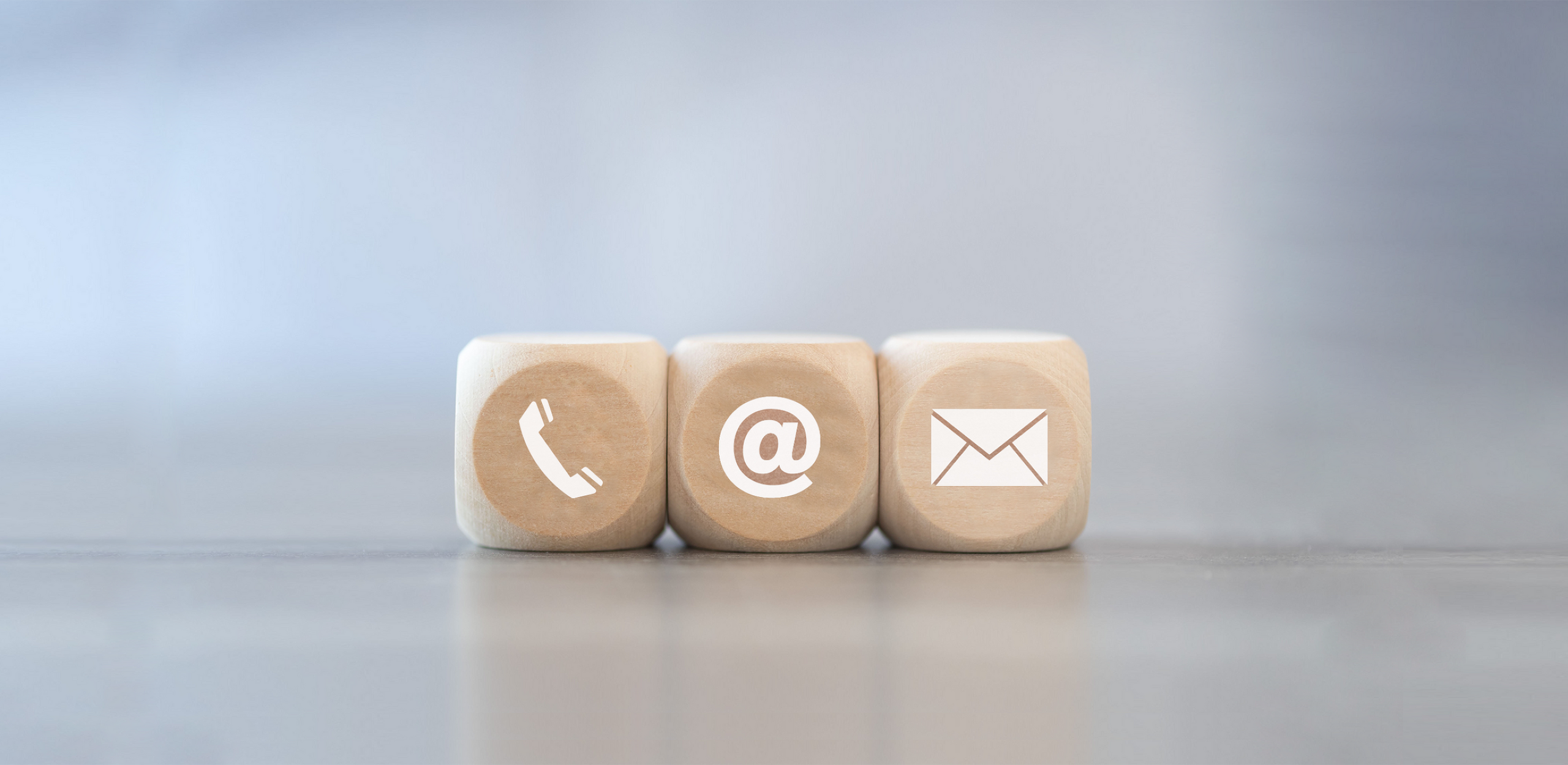 Contact Three wooden cubes, each displaying a different contact symbol: a telephone handset, an @ symbol, and an envelope, representing various ways to get in touch