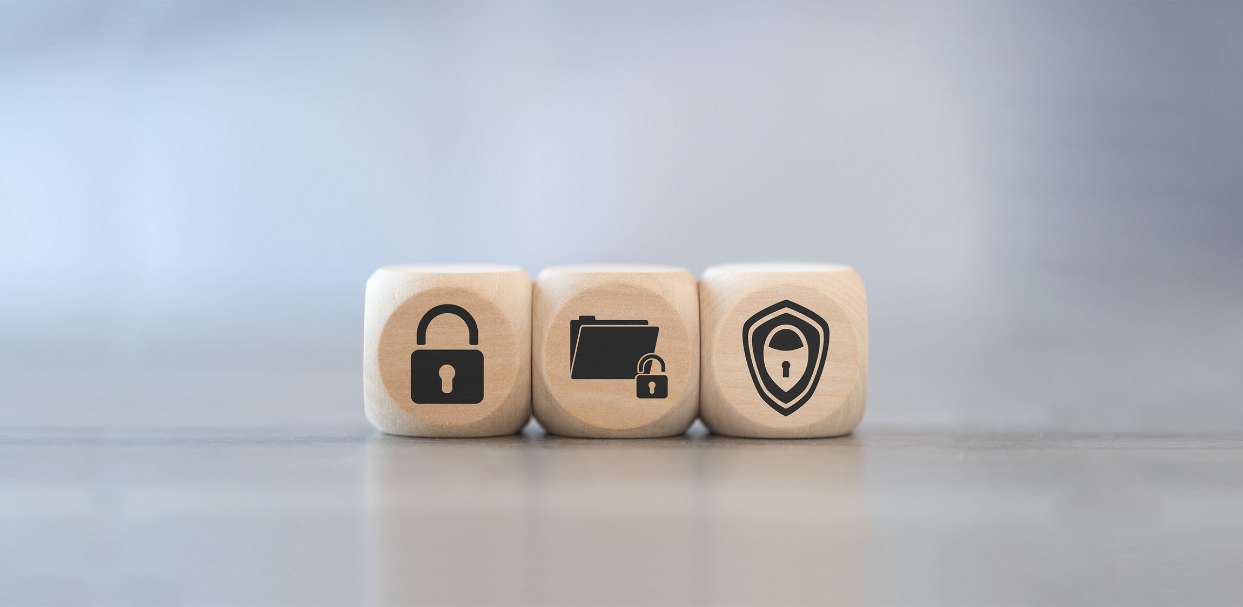 Three wooden cubes, each featuring a symbol: a padlock, a folder with a lock, and a shield.
