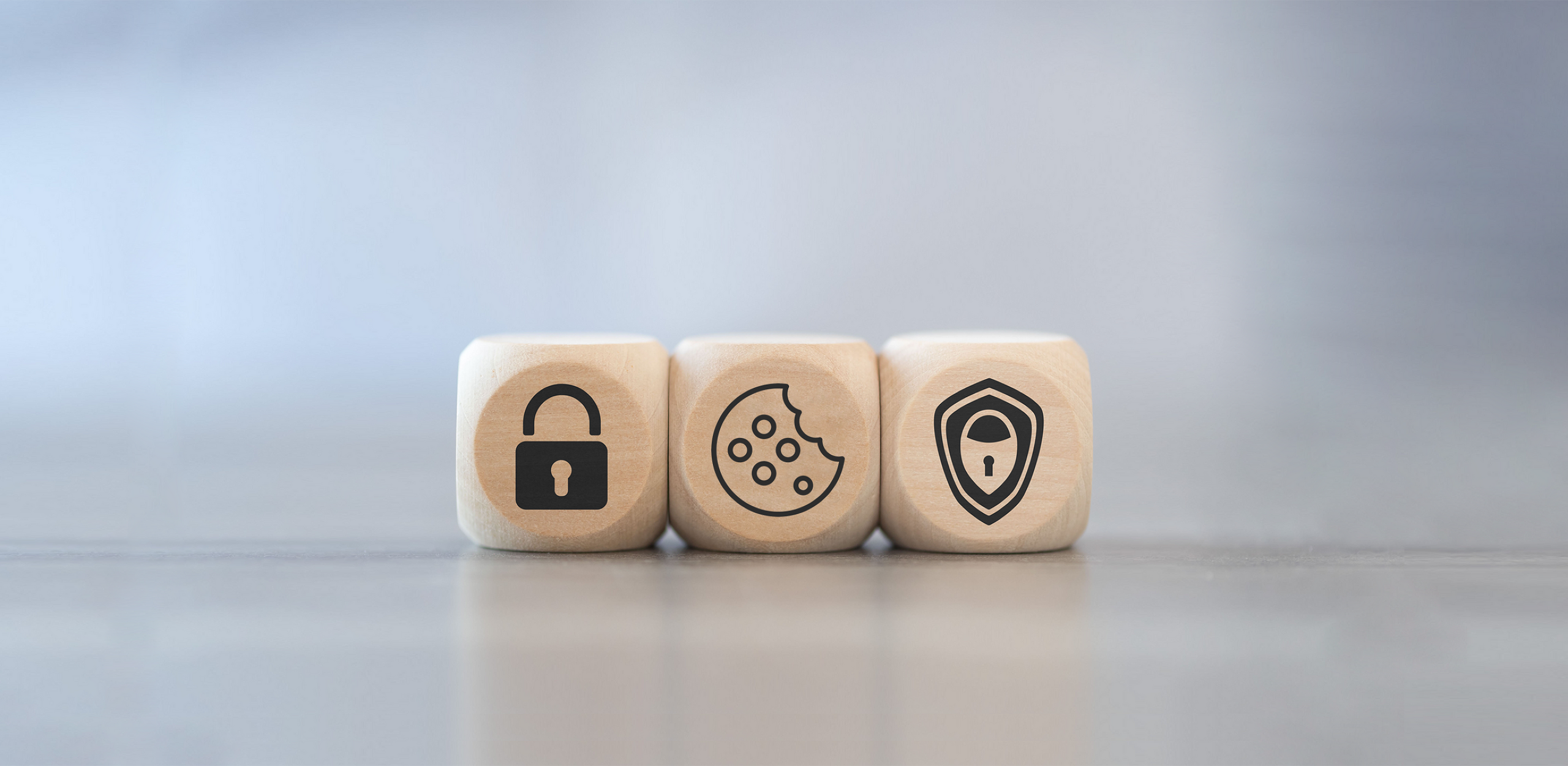 Three wooden cubes, each featuring a symbol: a padlock, a cookie and a shield.